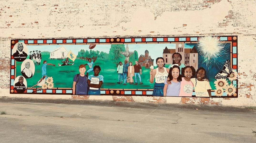 Children playing near a mural on a community centre wall