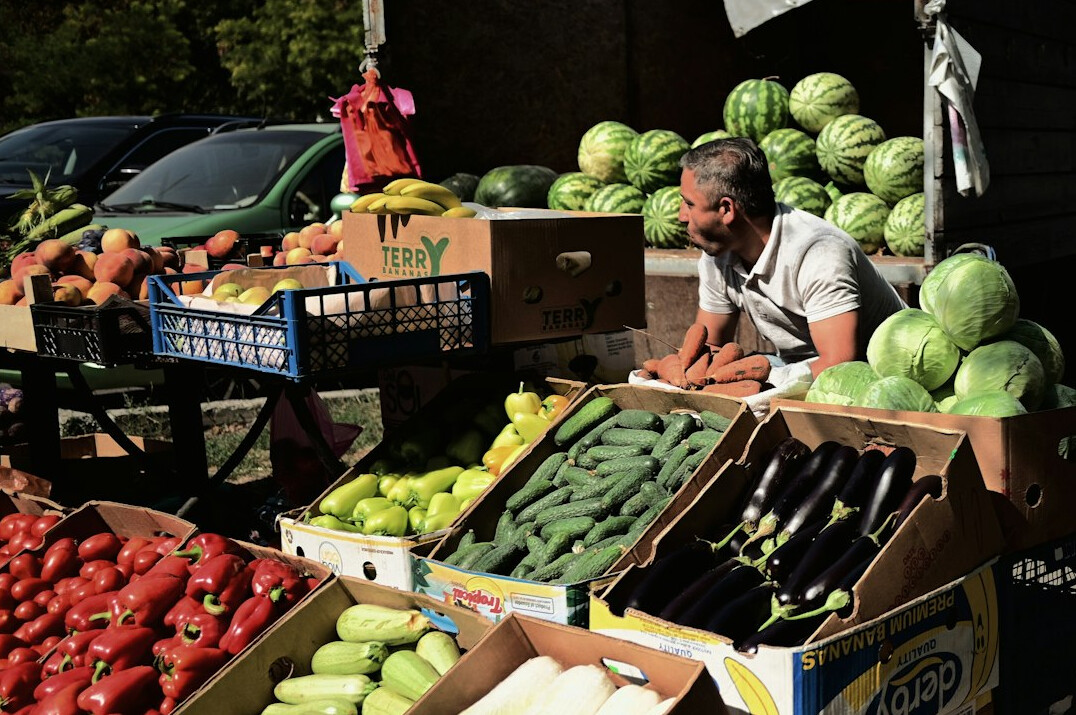 Vendor arranging produce at an outdoor farmers market